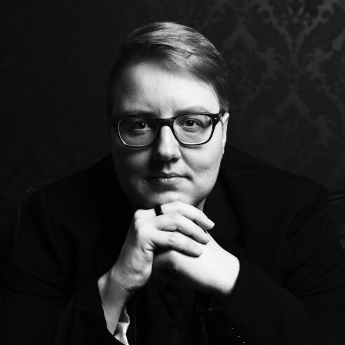 Foto von Tristan Lánstad, ein ernst blickender weißer Mann mit kurzem dunkelblonden Haar und Brille